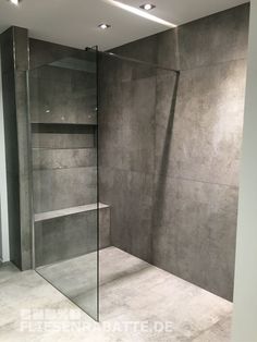 an empty bathroom with a glass shower door and shelves on the wall next to it