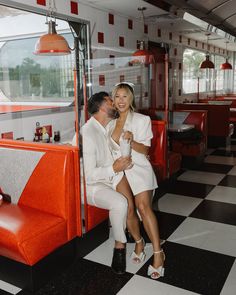 a man and woman are sitting on a bench in a diner with checkered flooring