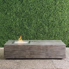 a fire pit sitting on top of a stone slab in front of a green wall