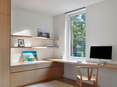 a desk with a computer on top of it next to a window in a room