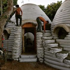 two men standing on top of stacks of sandbags in front of a building made out of cement