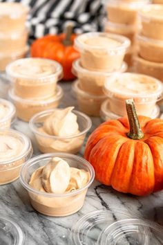 pumpkins and whipped cream in plastic containers on a marble table