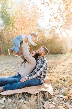 a man and woman are sitting on the ground with their toddler in his arms