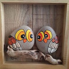 two painted rocks sitting on top of a wooden shelf