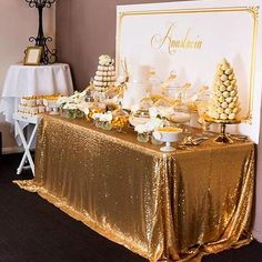 the dessert table is set up with gold sequins and white flowers on it