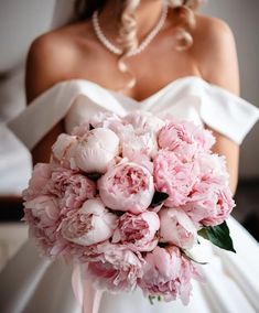 a bride holding a bouquet of pink peonies