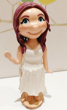 a figurine of a girl with red hair wearing a white dress and holding a yellow balloon