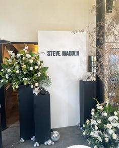 three black vases with flowers in them on display at a flower shop or show