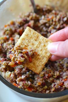 a person dipping crackers into a bowl full of food