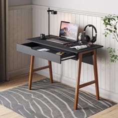 a desk with a laptop and headphones on it in front of a white wall