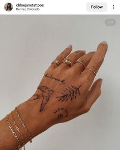 a woman's hand with tattoos on her left wrist and two rings on the palm