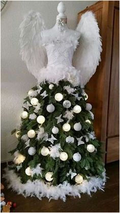 a white christmas tree with angel wings on it's top and lights around the base