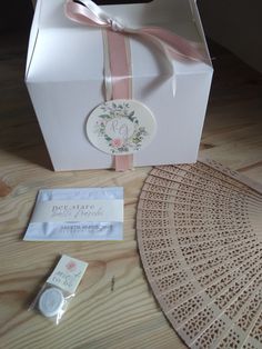 a white box with a pink ribbon around it and some other items on the table