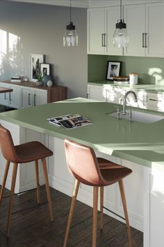 a kitchen island with two chairs next to it in front of a sink and cabinets