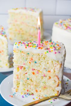 a slice of cake with white frosting and sprinkles is on a plate