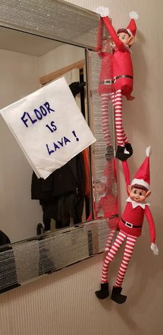 two elfs hanging on the wall in front of a mirror with a sign that says floor is lava