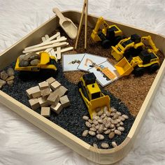 a wooden tray filled with construction vehicles and rocks