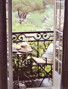 an open door leading to a balcony with a table and chairs on top of it