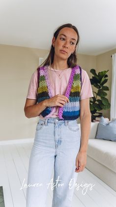 a woman standing in front of a couch wearing a pink shirt and blue jeans