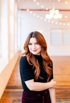 a woman standing in an empty room with her arms crossed and looking at the camera