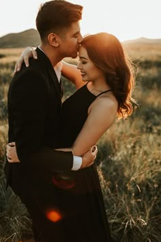 a man and woman embracing in an open field with the sun shining down on them