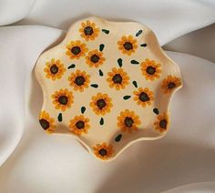 a yellow and white plate with sunflowers on it sitting on a white cloth