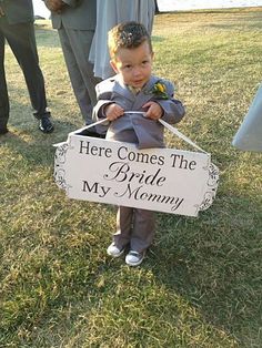 a little boy holding a sign that says here comes the bride my mommy