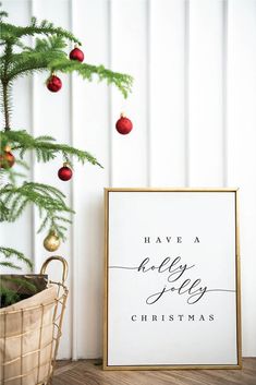 a christmas tree next to a white and gold framed sign with the words have a holly for christmas