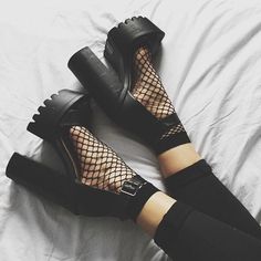 a woman laying on top of a white bed wearing black shoes and fishnet stockings