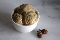 a white bowl filled with ice cream next to two acorns