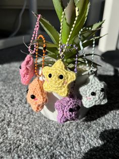 small crocheted animal keychains are hanging from a potted plant on the floor