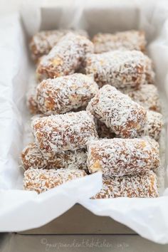 a box filled with lots of powdered sugar covered treats on top of white paper