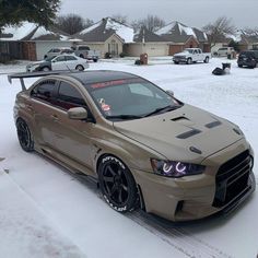 a tan car parked in the snow near some houses