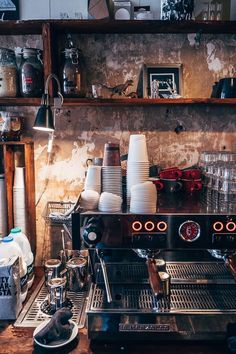 an espresso machine sitting on top of a counter next to cups and saucers