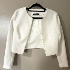 a white jacket hanging up on a wall next to a hanger with black pins