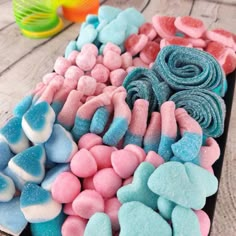 a tray filled with lots of different colored marshmallows on top of a wooden table