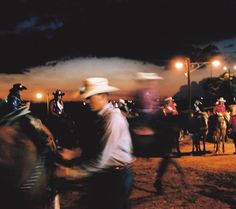 a man riding on the back of a horse next to other people at a rodeo