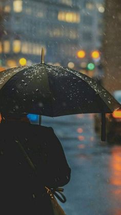 a person standing in the rain holding an umbrella over their head and looking at traffic