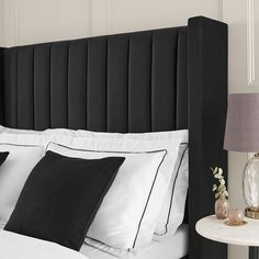 a bed with black headboard and white sheets, two night stands on either side