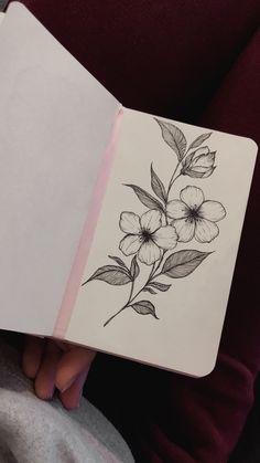 a person holding an open notebook with flowers on it