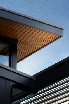 the corner of a building with an open window and sky in the backround