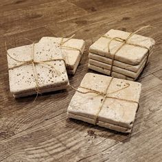 four square pieces of white soap tied with twine on a wooden surface, sitting next to each other