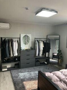 a bedroom with a bed, dressers and clothes hanging on the racks in it