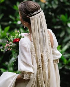 the back of a woman's head wearing a veil and dress with flowers on it