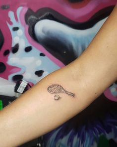 a tennis racket and ball tattoo on the arm