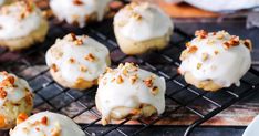 a bunch of cookies that are sitting on a cooling rack with white frosting and pecans