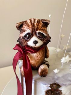 a cake decorated with a raccoon and red ribbon