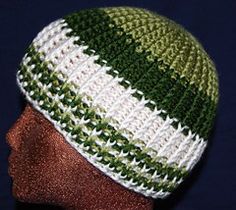 a green and white knitted hat on top of a mannequin's head