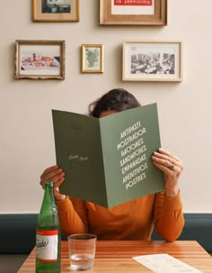 a woman sitting at a table reading a book