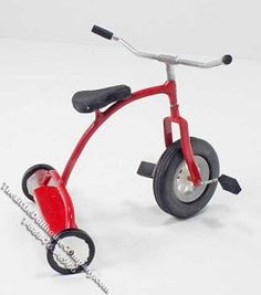 a red tricycle is shown on a white surface with black spokes and wheels